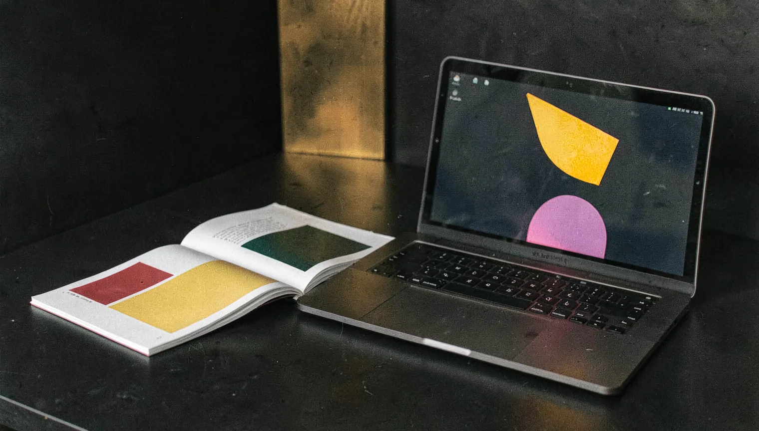 A calm studio desk with a brand book, swatches, and a laptop