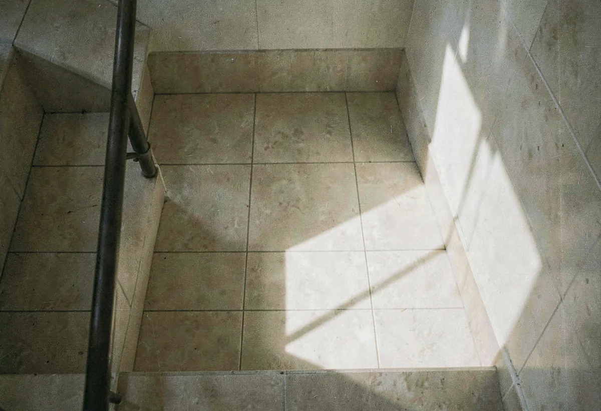 A stairwell shadow falling across pale tile
