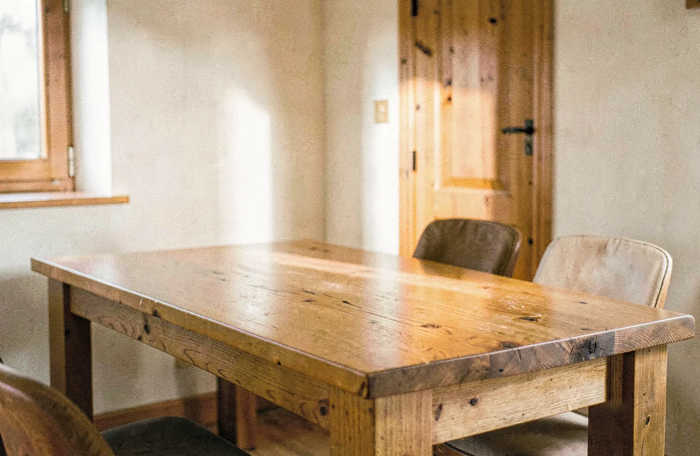 A long solid-wood dining table in a calm sunlit room