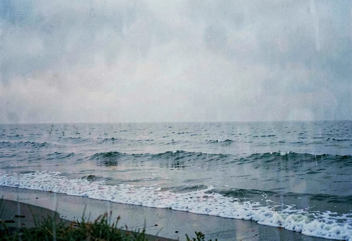 Rain moving across a grey sea from the shore