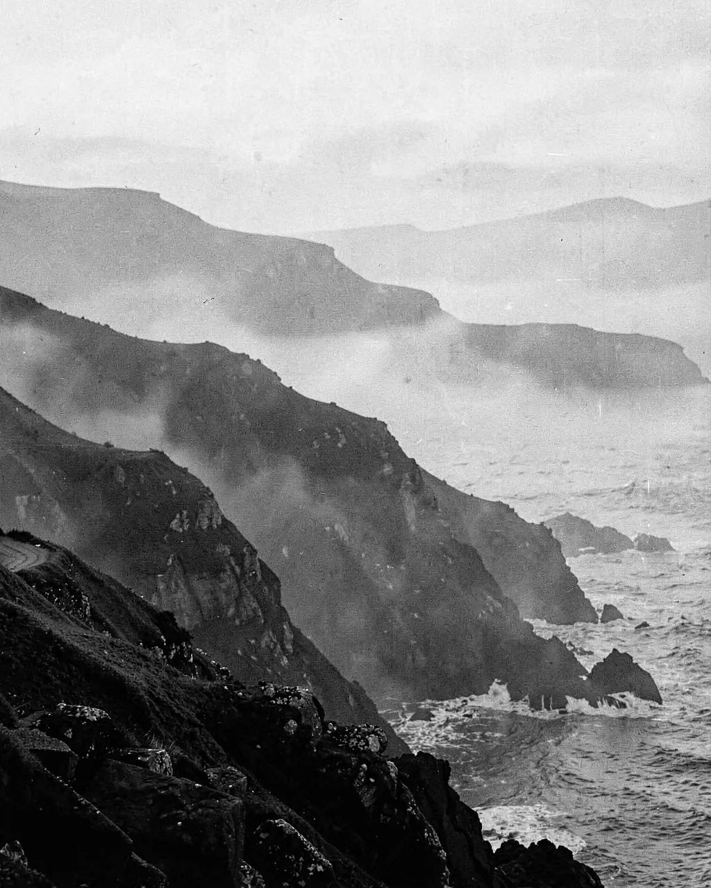 Mist over a dark headland at first light