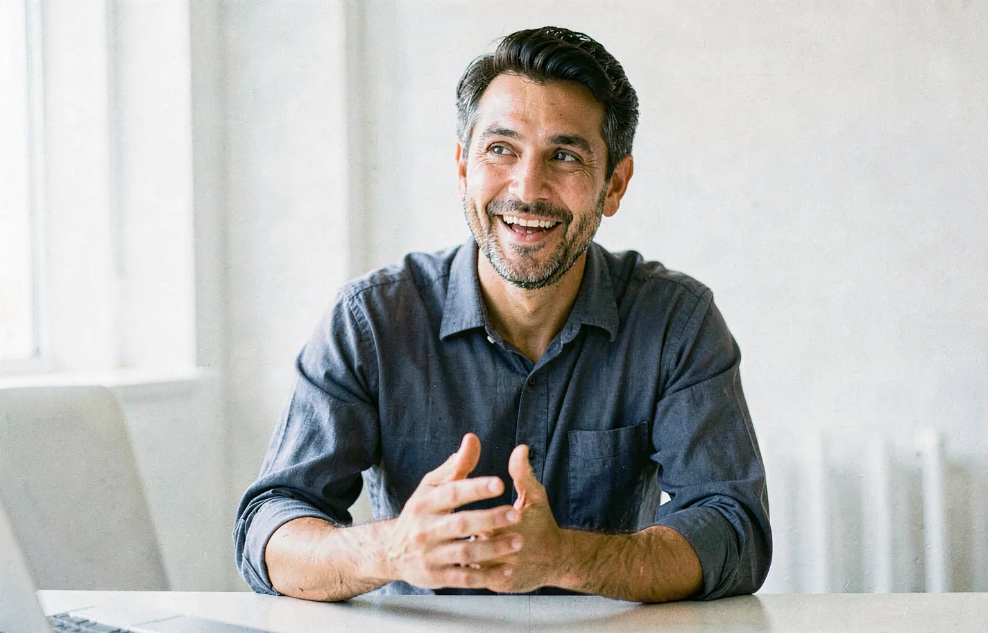 A founder at a plain desk mid-conversation, sleeves rolled up