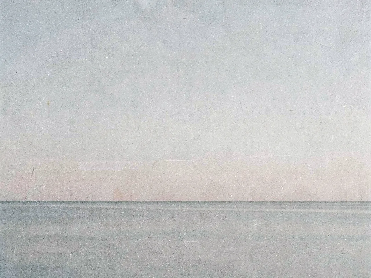 A low grey horizon where a flat tide meets a pale morning sky